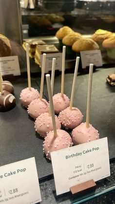 cake pops with pink frosting and sprinkles are on display in a bakery