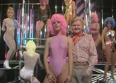 man and woman standing in front of mannequins with pink hair on stage