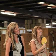 two women standing next to each other near a ping pong table