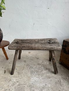 a wooden bench sitting next to a potted plant on top of a cement floor