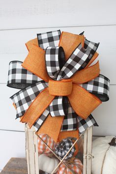 an orange and black bow on top of a wooden crate with pumpkins in the background