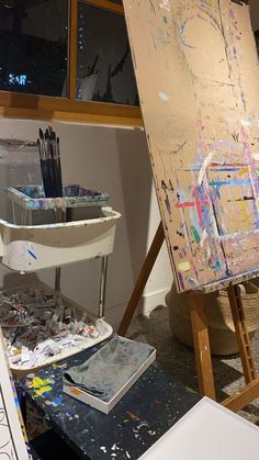 an artist's easel with paint and brushes on it