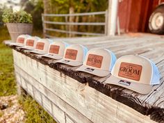 six hats are lined up on the side of a wooden fence in front of a barn