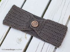 a crocheted headband with buttons on it sitting on a white wooden surface