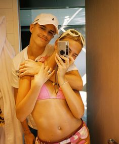 a man and woman taking a selfie in front of a mirror while wearing bathing suits