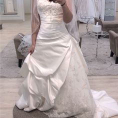 a woman in a wedding dress taking a selfie with her cell phone while wearing a veil