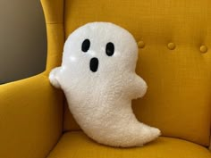 a stuffed ghost sitting on top of a yellow chair