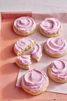 pink frosted cookies on a tray with one cut in half