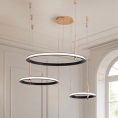 three circular lights hanging from the ceiling in a room with white walls and windows,