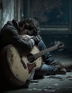 a man sitting on the floor with his guitar in front of him and looking down