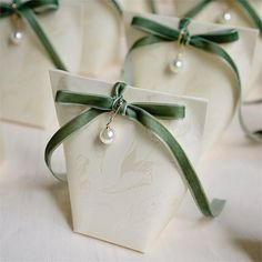 four white boxes with green ribbons and pearls