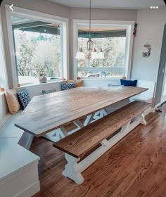 a large wooden table sitting in the middle of a living room next to a window