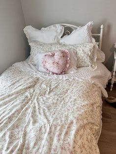 a white bed topped with pillows and a pink stuffed animal on it's side