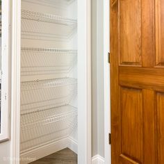 an empty pantry with wooden doors and shelving unit in the corner next to it