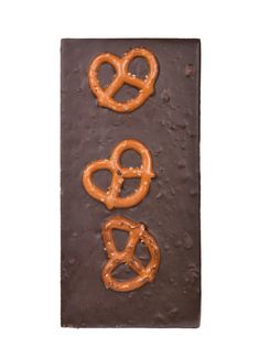 three pretzels are on top of a chocolate bar that is decorated with frosting