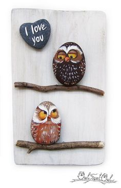 two owls sitting on top of a tree branch next to a stone with i love you written on it