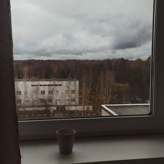 a cup sitting on top of a window sill in front of a large building