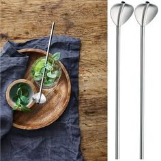 three stainless steel spoons on a wooden plate and one is holding a green drink