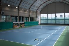 an indoor tennis court is shown in this 3d image, with two people playing on the sidelines