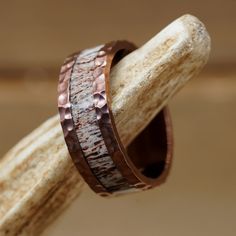 two wedding bands made out of copper and silver are sitting on top of a piece of wood