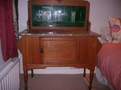 an old wooden cabinet with marble top in a bedroom next to a radiator