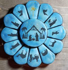 a blue cake decorated with nativity scene on top of a wooden table next to a star