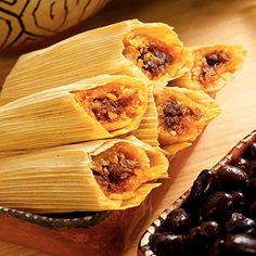 several tamales with raisins on a wooden cutting board next to some dates