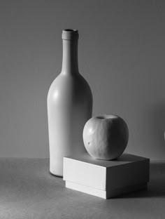 two white vases sitting on top of a table next to an apple and a bottle