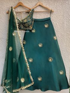 This emerald green blouse and lehenga in threadwork and sequins work embroidery is perfect for a mehendi or cocktail event.  It is teamed with a green net dupatta with gold border work and scattered butis. Green Sets With Zari Work For Reception, Green Anarkali Set For Diwali Reception, Festive Green Anarkali Set For Reception, Green Festive Sets For Reception, Festive Green Sets For Reception, Green Festive Sets For Receptions, Green Anarkali Sharara For Reception, Green Sharara For Reception, Elegant Green Sharara With Gota Work