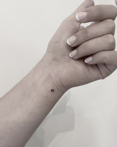 a woman's hand with a tiny black dot tattoo on the middle of her left wrist