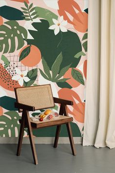 a chair sitting in front of a wall with flowers and leaves painted on the walls