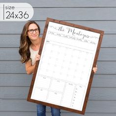 a woman holding up a large wooden framed calendar