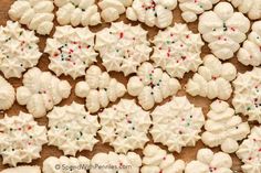 white sugar cookies with sprinkles on a wooden surface, ready to be cut into snowflakes