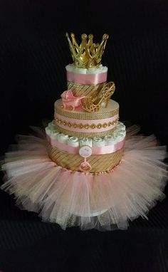 a three tiered cake with pink and gold decorations on the top, sitting on a black surface