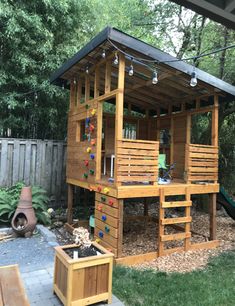 a wooden play house in the backyard with stairs leading up to it's roof