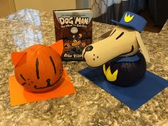 a dog in a pumpkin hat next to a book on a counter top with other items