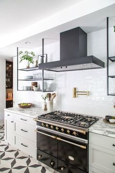 a kitchen with black and white tile flooring and an oven hood over the stove