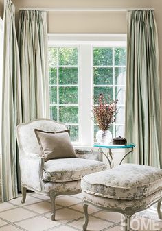 a chair and ottoman in front of a window with drapes on the windowsill