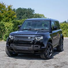 a black land rover is parked on the gravel