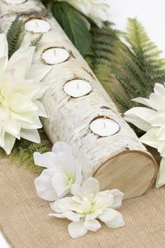 some white flowers and candles are sitting on a burlap tablecloth with wood