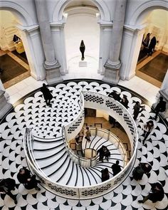 people are walking up and down the stairs in an ornate building with black and white tiles