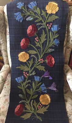 a blue blanket with flowers and butterflies on it sitting in a chair next to a wall