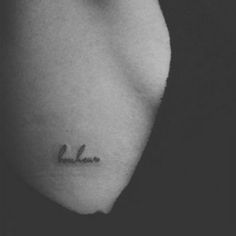 a black and white photo of a woman's shoulder with the word believe tattooed on it