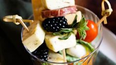 a glass filled with fruit and cheese on top of a table