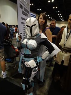 a woman standing next to a man in a star wars cosplay costume on display