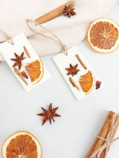 an orange cut in half next to cinnamon sticks and star anise on a white surface