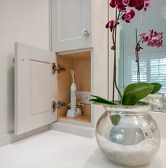 a vase filled with pink flowers sitting on top of a counter next to a mirror