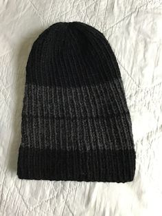 "Black gray hand Knit winter beanie hat with pompom Measures  14\" around, easily stretches to 22\" 10.5\" long  acrylic (75%) wool (25%) blend. machine wash inside out on gentle and dry low Here's a basic black and gray hand knit winter hat for keeping your ears warm. Knitted as one size fits most. The color is gender neutral with   a predominant black hat with a thick gray stripe  a small black stripe.  Perfect for a man or woman.  Will also fit a child. A great basic beanie to wear outside in Upcycled Neckties, Cotton Beanie, Yarn Hats, Warm Winter Hats, Black Beanie, Grey Beanie, Grey Scarf, Winter Cap, Winter Hats Beanie