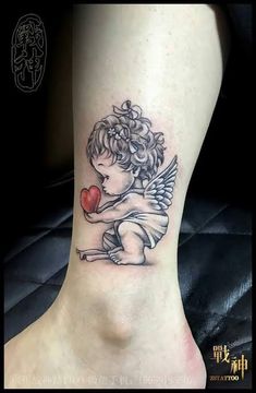 an angel with a heart tattoo on the ankle