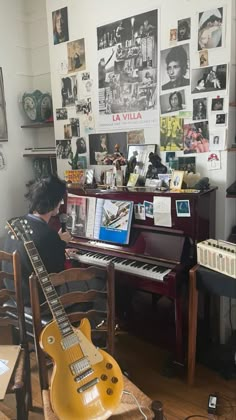 a person sitting at a piano in front of a wall with pictures and guitars on it